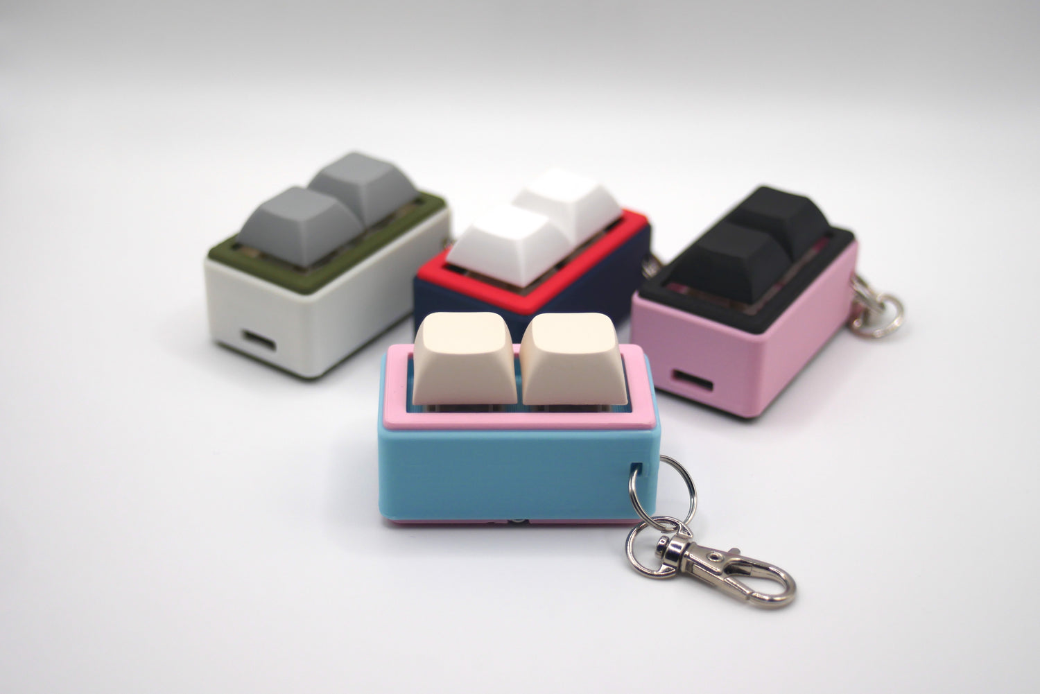 Four customizable macropad keychains in pink, light blue, green, red, and black made by TogKey