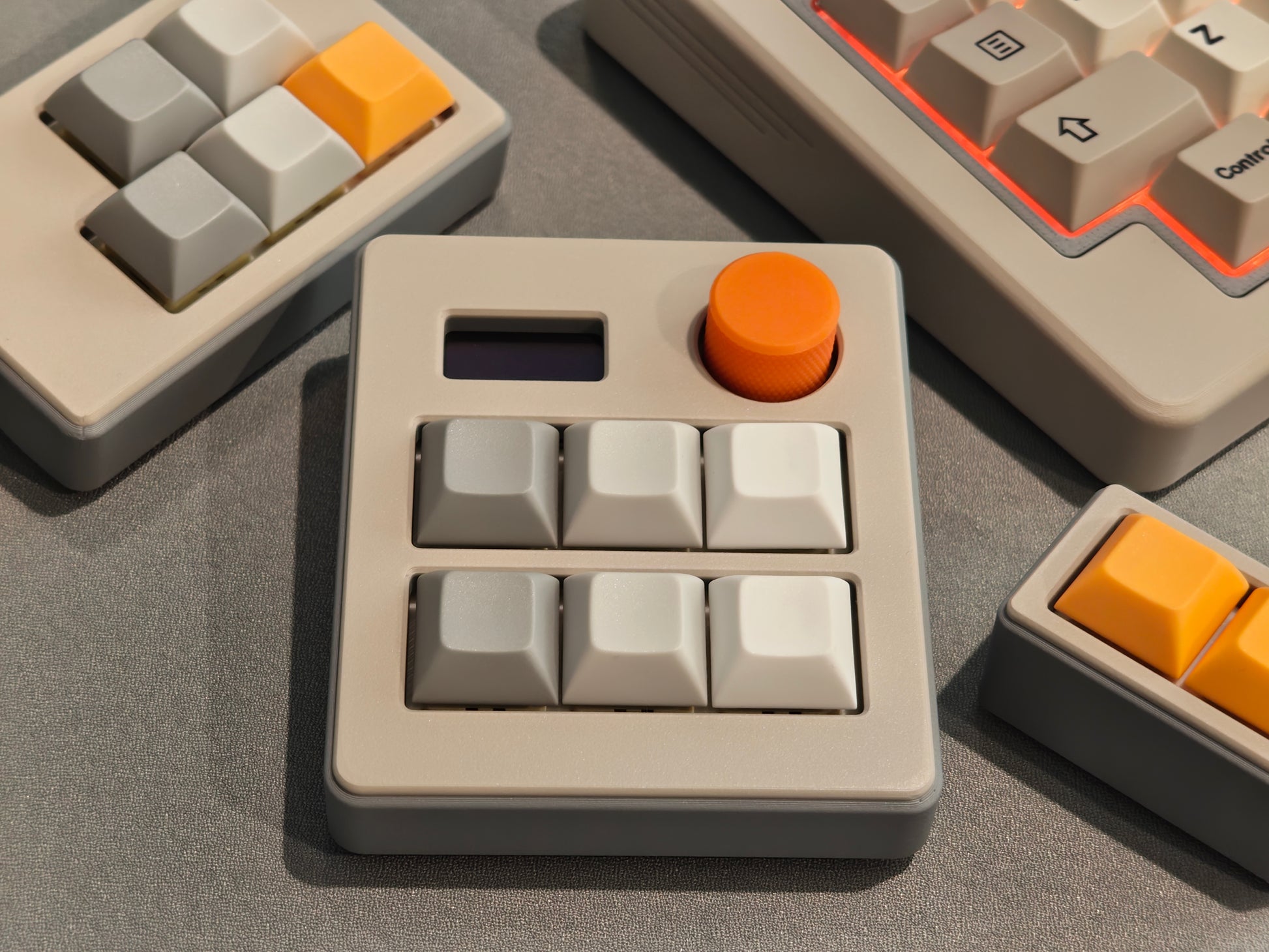 Close-up of a mechanical keyboard with beige and orange keycaps on a gray surface.